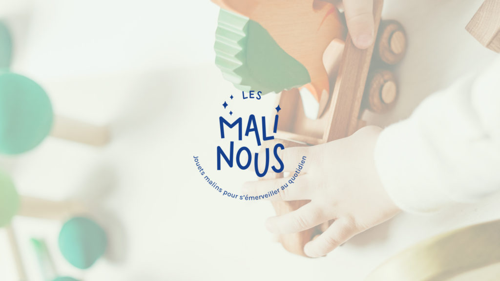 Logo typographique de Les Malinous - Jouets malins pour s'émerveiller au quotidien, sur une photo représentant les mains d'un enfant jouant avec un jouet en bois